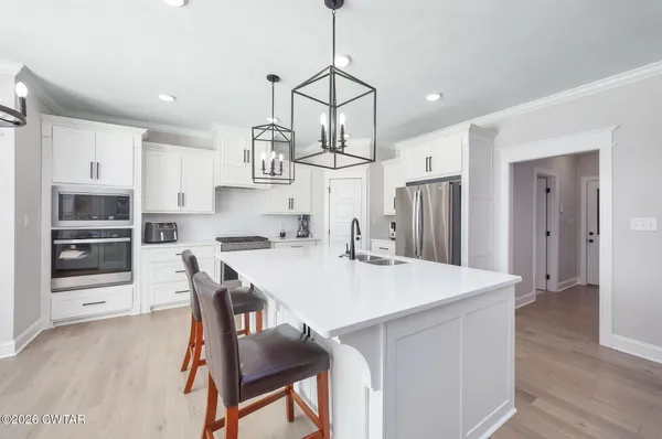 a kitchen with stainless steel appliances a dining table chairs refrigerator and cabinets