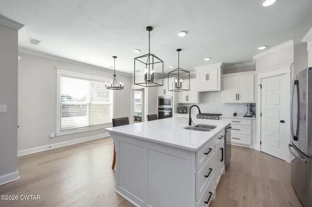 a kitchen that has a sink a center island stainless steel appliances and cabinets