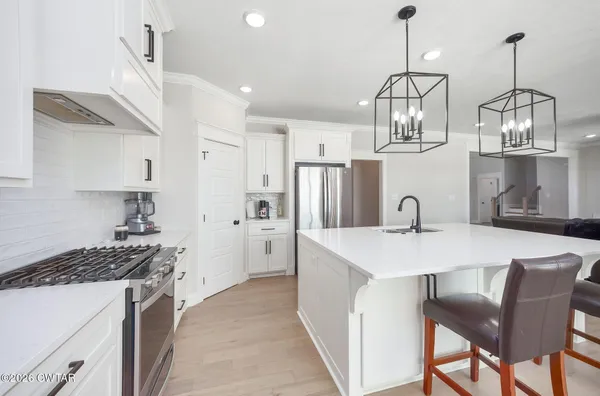 a kitchen with stainless steel appliances a table chairs stove and refrigerator