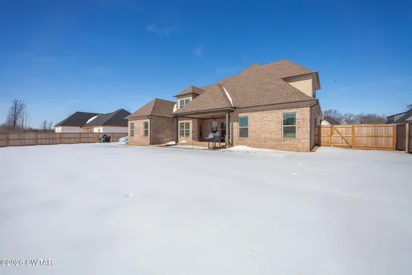a front view of a house with a large tree in front of it