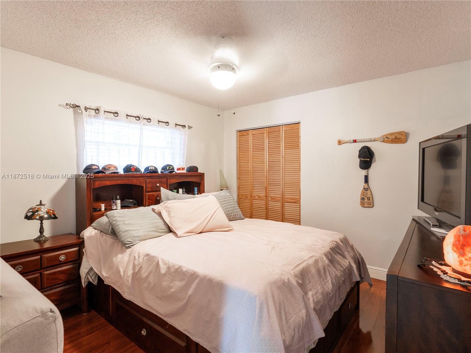 15275 Southwest 56th Terrace Miami, FL 33193 - Photo 14 of 32 a bedroom with a bed and a flat tv screen on a dresser