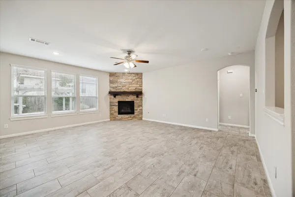 an empty room with chandelier fan and windows