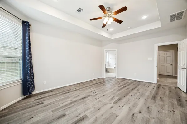 an empty room with wooden floor and ceiling fan