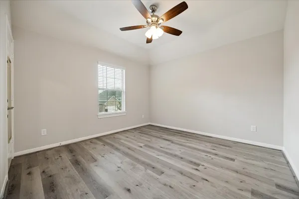 an empty room with wooden floor ceiling fan and window
