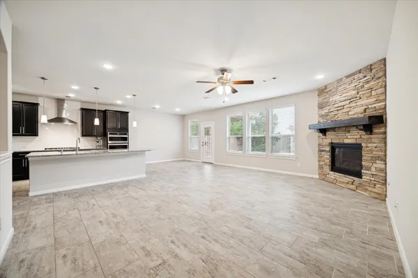 a view of an empty room with a kitchen and a fireplace