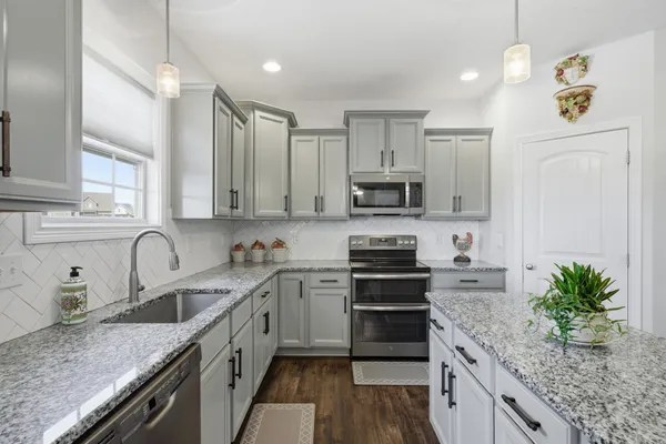 a kitchen with stainless steel appliances granite countertop a sink a stove top oven a refrigerator cabinets and a counter top space