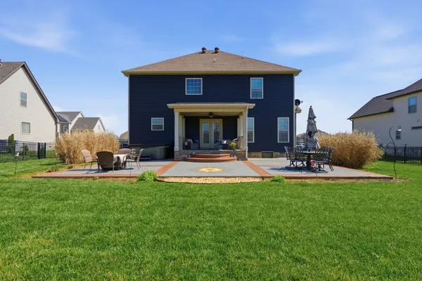 a view of a house with a yard fire pit and a large tree