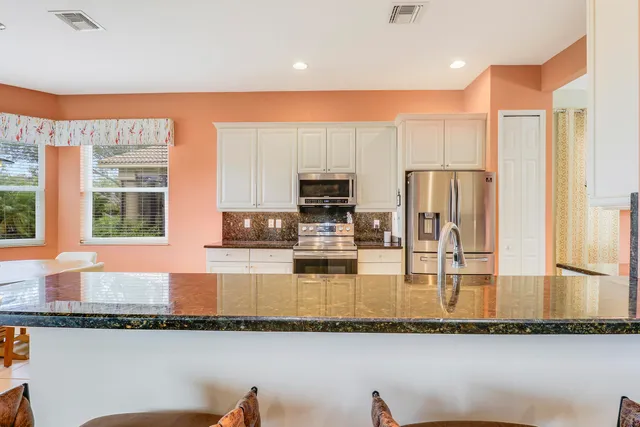 a kitchen with stainless steel appliances granite countertop a refrigerator a stove and a sink with wooden floor