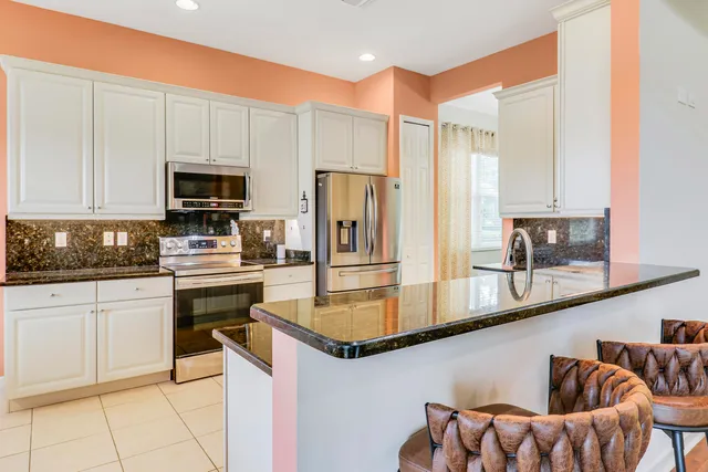 a kitchen with stainless steel appliances a refrigerator a stove a sink and white cabinets