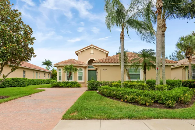 a front view of a house with a garden and trees