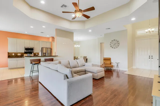 a living room with furniture kitchen view and a wooden floor