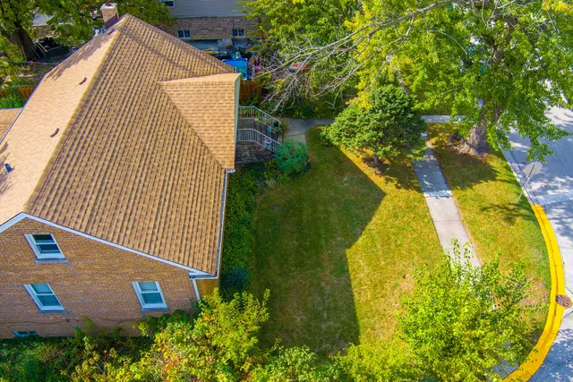 an aerial view of a house with swimming pool and large trees