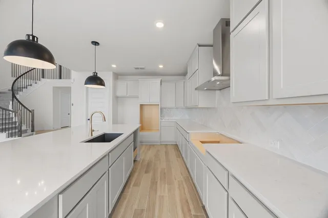 a kitchen with stainless steel appliances granite countertop a sink a stove and a wooden floors