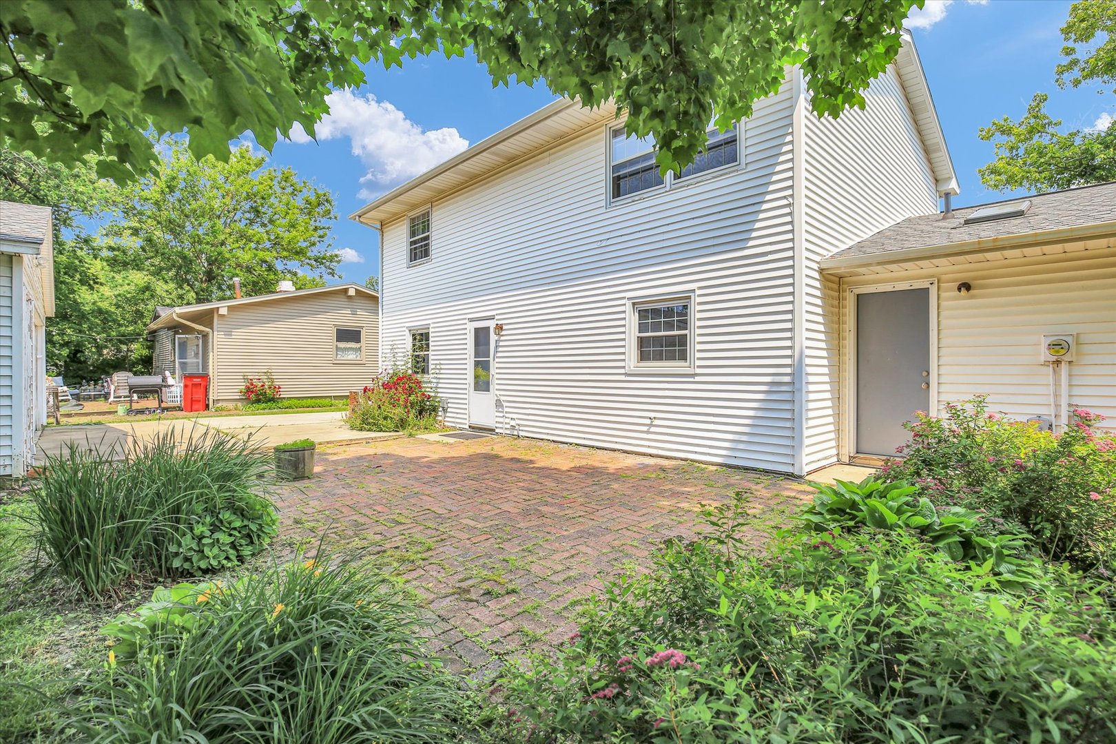 2107 Barberry Drive Champaign, IL 61821 - Photo 33 of 37 a backyard of a white house with potted plants and a large tree