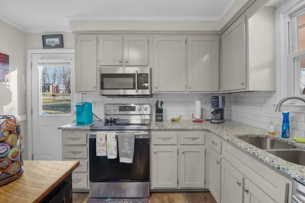 a kitchen with stainless steel appliances granite countertop a stove top oven a sink a dining table and chairs