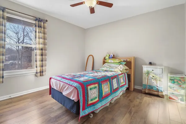 a bedroom with a bed a dresser and a chandelier