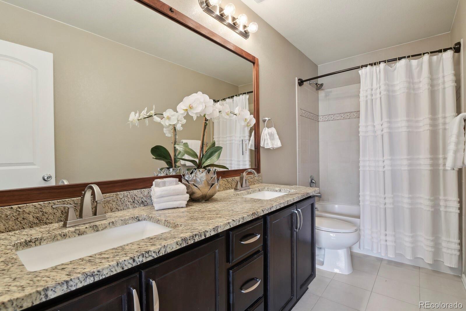 3495 Amber Sun Circle Castle Rock, CO 80108 - Photo 14 of 29 a bathroom with a granite countertop sink a toilet and a mirror