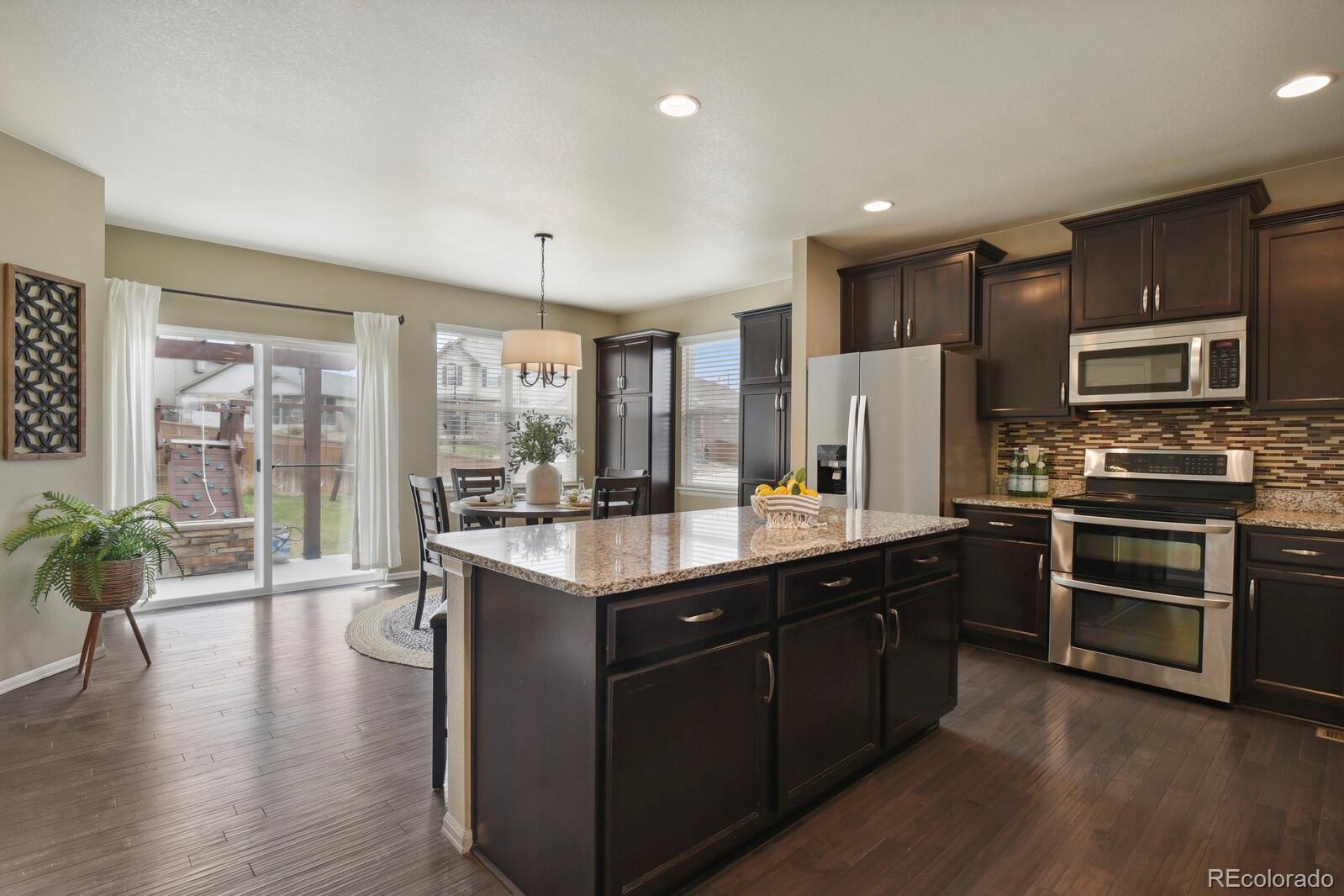 3495 Amber Sun Circle Castle Rock, CO 80108 - Photo 6 of 29 a kitchen with stainless steel appliances granite countertop a refrigerator a stove top oven a sink with wooden floor and cabinets