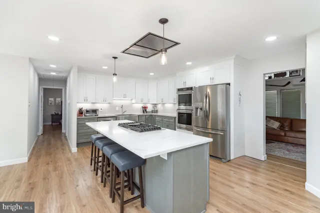 a kitchen with stainless steel appliances a sink a stove a refrigerator cabinets and wooden floor