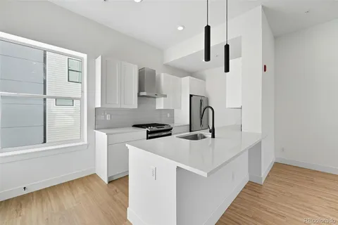 a kitchen with stainless steel appliances granite countertop a sink a stove a refrigerator and island with wooden floor
