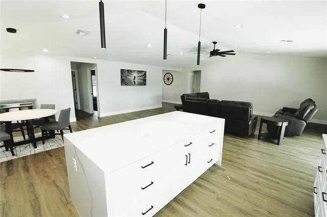 a large white kitchen with stainless steel appliances granite countertop a stove a refrigerator a oven and a dining table with wooden floor