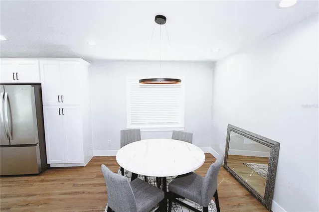 a kitchen with stainless steel appliances a refrigerator a stove a sink dishwasher with a dining table and chairs with wooden floor