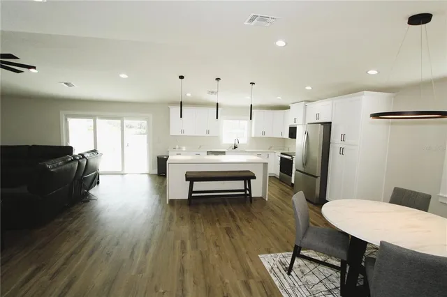 a living room with furniture kitchen view and a wooden floor