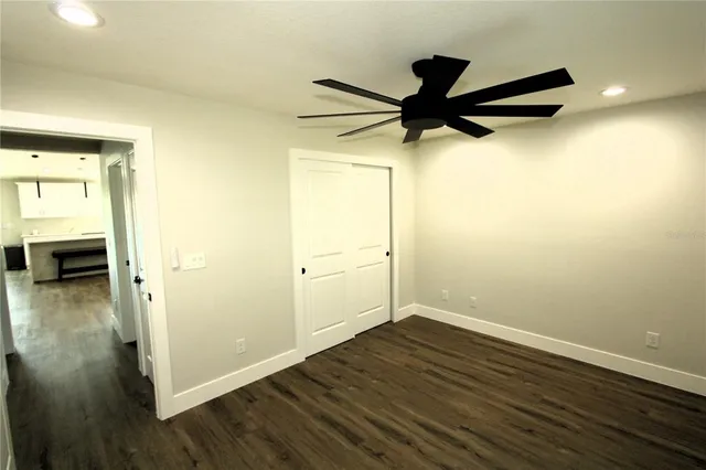 an empty room to ceiling fan and wooden floor