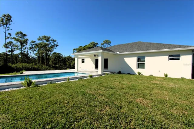 a view of swimming pool with seating space and trees in the background