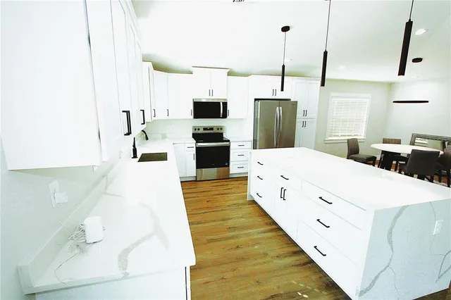 a large white kitchen with sink a refrigerator and a stove