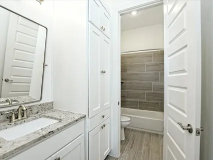 a bathroom with a granite countertop sink a mirror and a bathtub