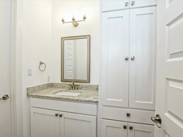a bathroom with a granite countertop sink and a mirror