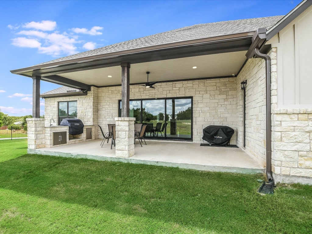 113 Tesoro Perdido Cove Liberty Hill, TX 78642 - Photo 29 of 31 a view of a patio with table and chairs and a barbeque with wooden fence