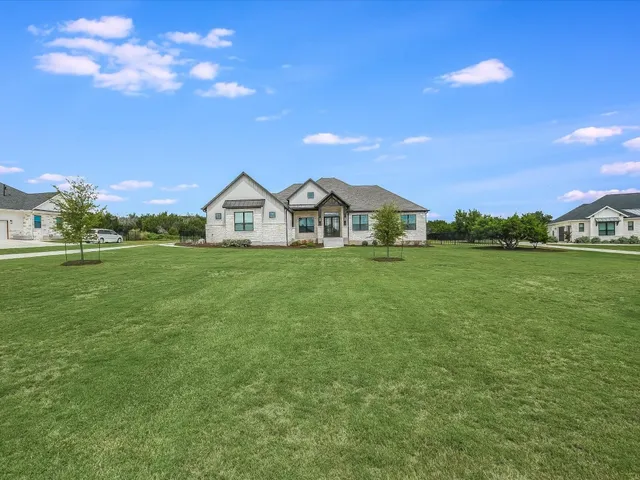 a view of a green field with house in the background