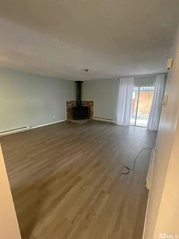 a view of an empty room with window and wooden floor