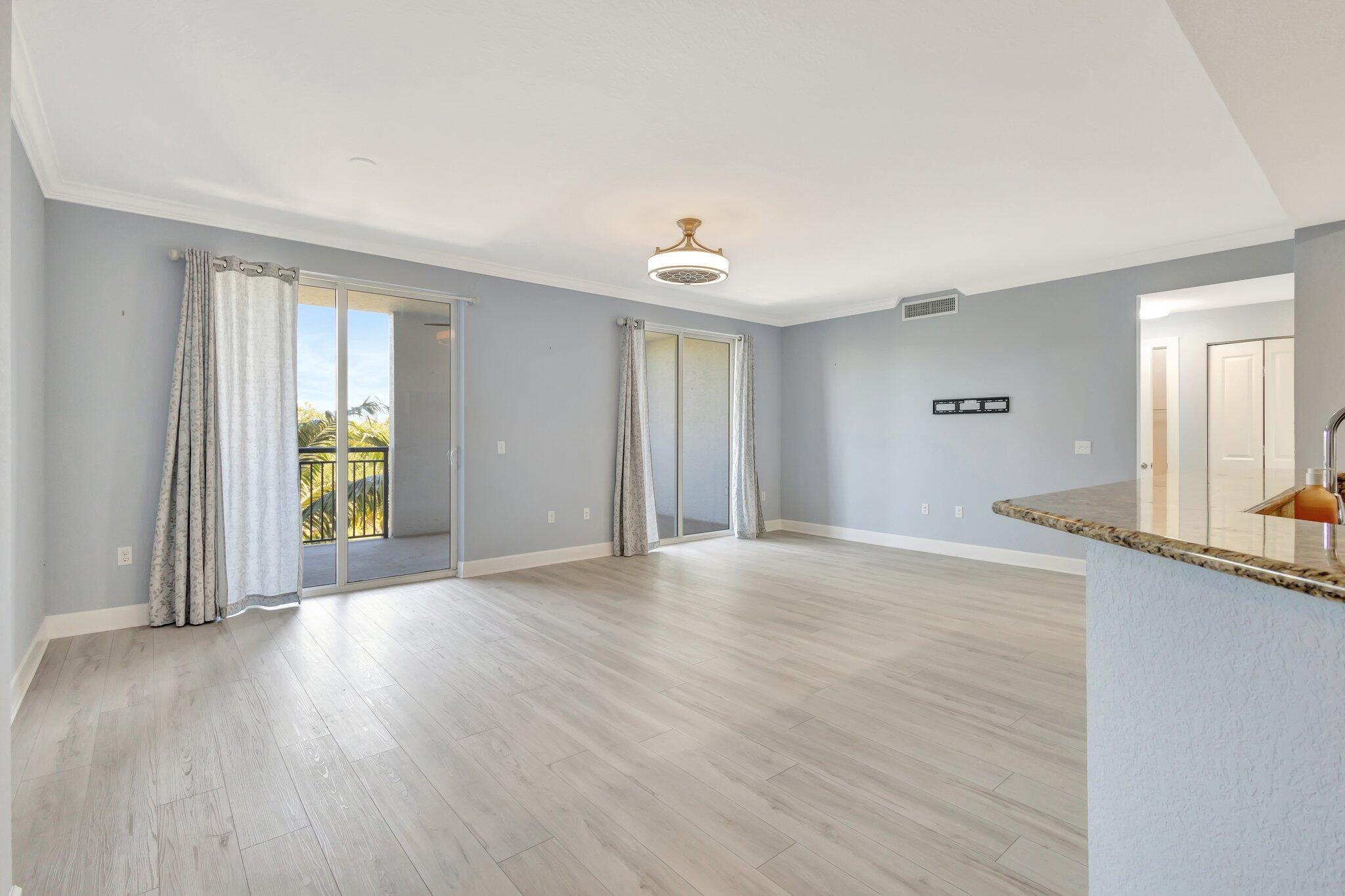 1690 Renaissance Commons Boulevard, Unit 1401 Boynton Beach, FL 33426 - Photo 34 of 41 an empty room with wooden floor and windows