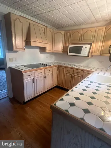 a kitchen with stainless steel appliances granite countertop a sink a stove a microwave oven cabinets and wooden floor