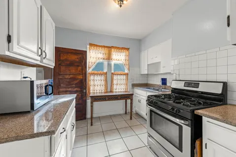a kitchen with granite countertop a stove top oven sink and cabinets
