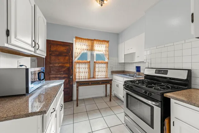 a kitchen with granite countertop a stove top oven sink and cabinets