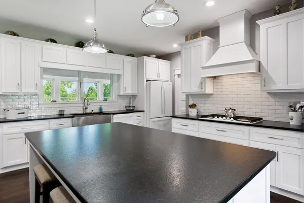 a kitchen with stainless steel appliances granite countertop a sink a stove and a refrigerator