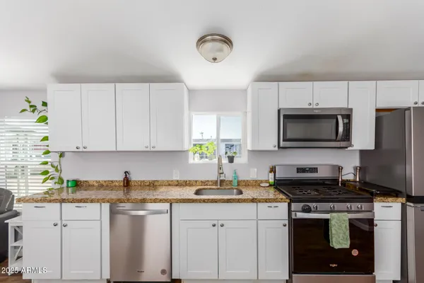 a kitchen with stainless steel appliances granite countertop a sink a stove a microwave a refrigerator and cabinets