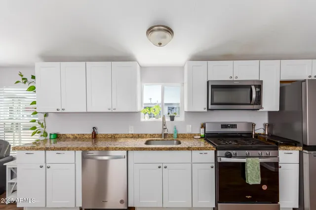 a kitchen with stainless steel appliances granite countertop a sink a stove a microwave a refrigerator and cabinets