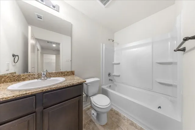 a bathroom with a granite countertop sink toilet a mirror and shower
