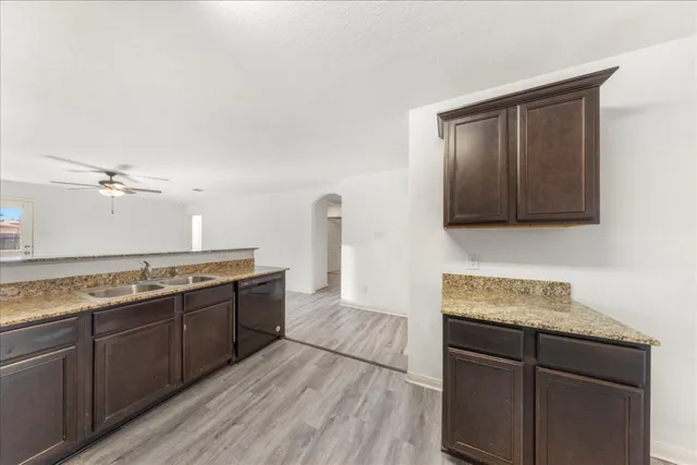 a kitchen with granite countertop a sink cabinets and wooden floor