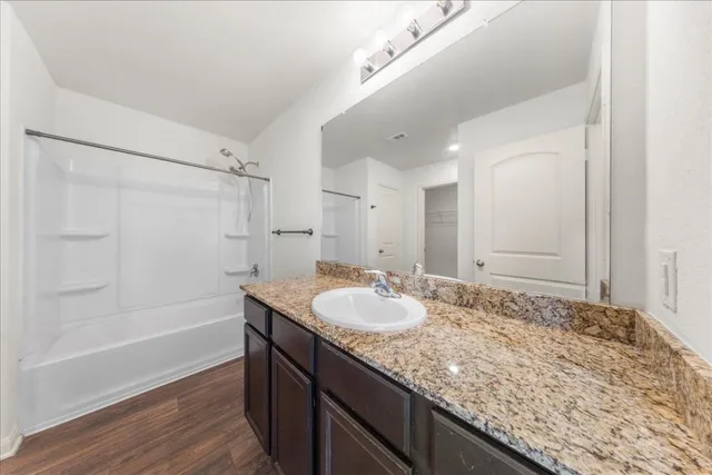 a bathroom with a granite countertop sink a mirror and a bathtub