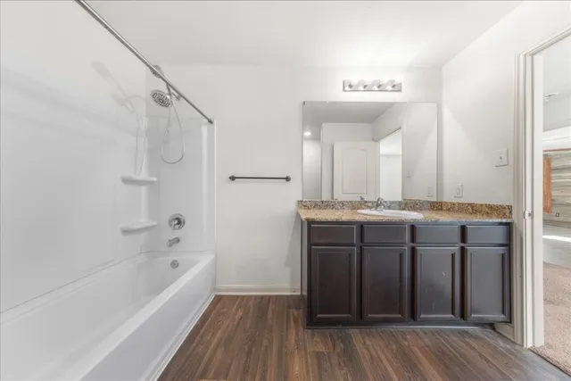 a bathroom with a granite countertop sink mirror and a bathtub