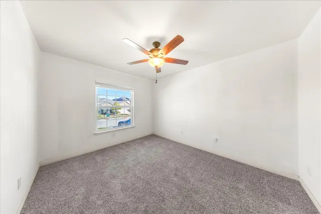 an empty room with bed and a chandelier fan