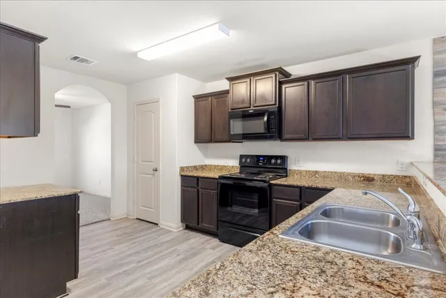 a kitchen with stainless steel appliances granite countertop a stove a sink and a refrigerator
