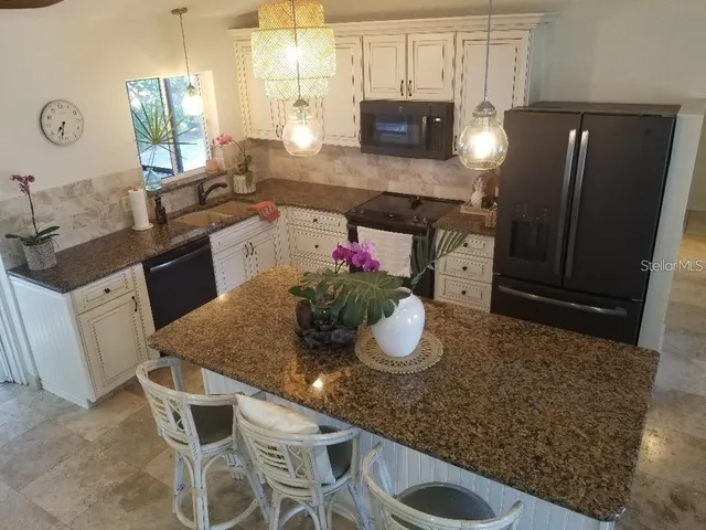 a kitchen with stainless steel appliances granite countertop a sink a stove a microwave a refrigerator and cabinets