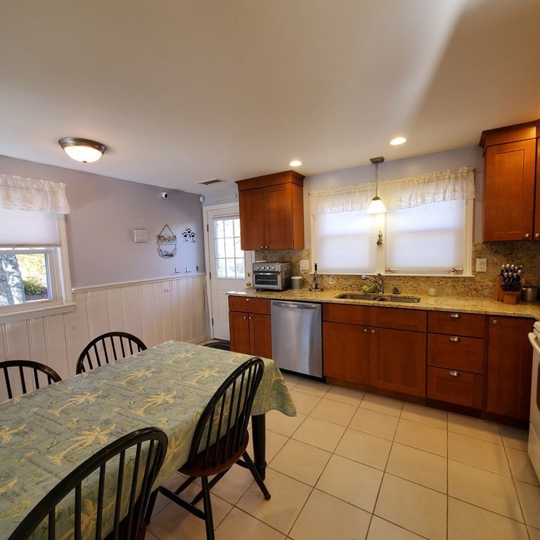 45 Nipigon Way West Dennis, MA 02639 - Photo 12 of 42 a kitchen with granite countertop a stove a sink a dining table and chairs